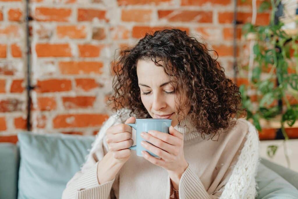 Woman sitting with a cup of coffee, representing pausing to balance your life with a simple, calming moment