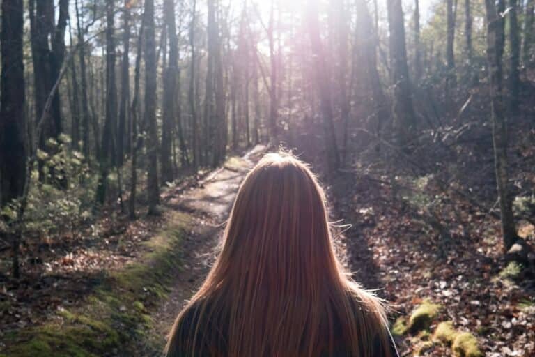 Woman walking alone along a quiet path, representing reflection during a values conflict and the process of making intentional choices.