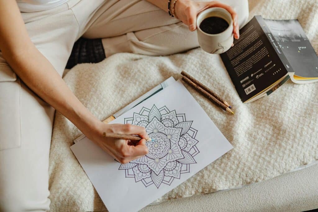 Woman relaxing with a book, colouring book and cup of coffee - an example of hobbies for relaxation. 