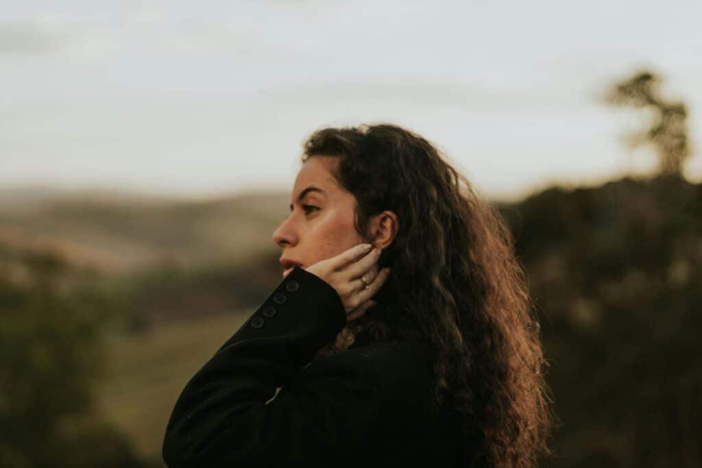 Woman outdoors pausing to reflect on the cost of saying yes to everything